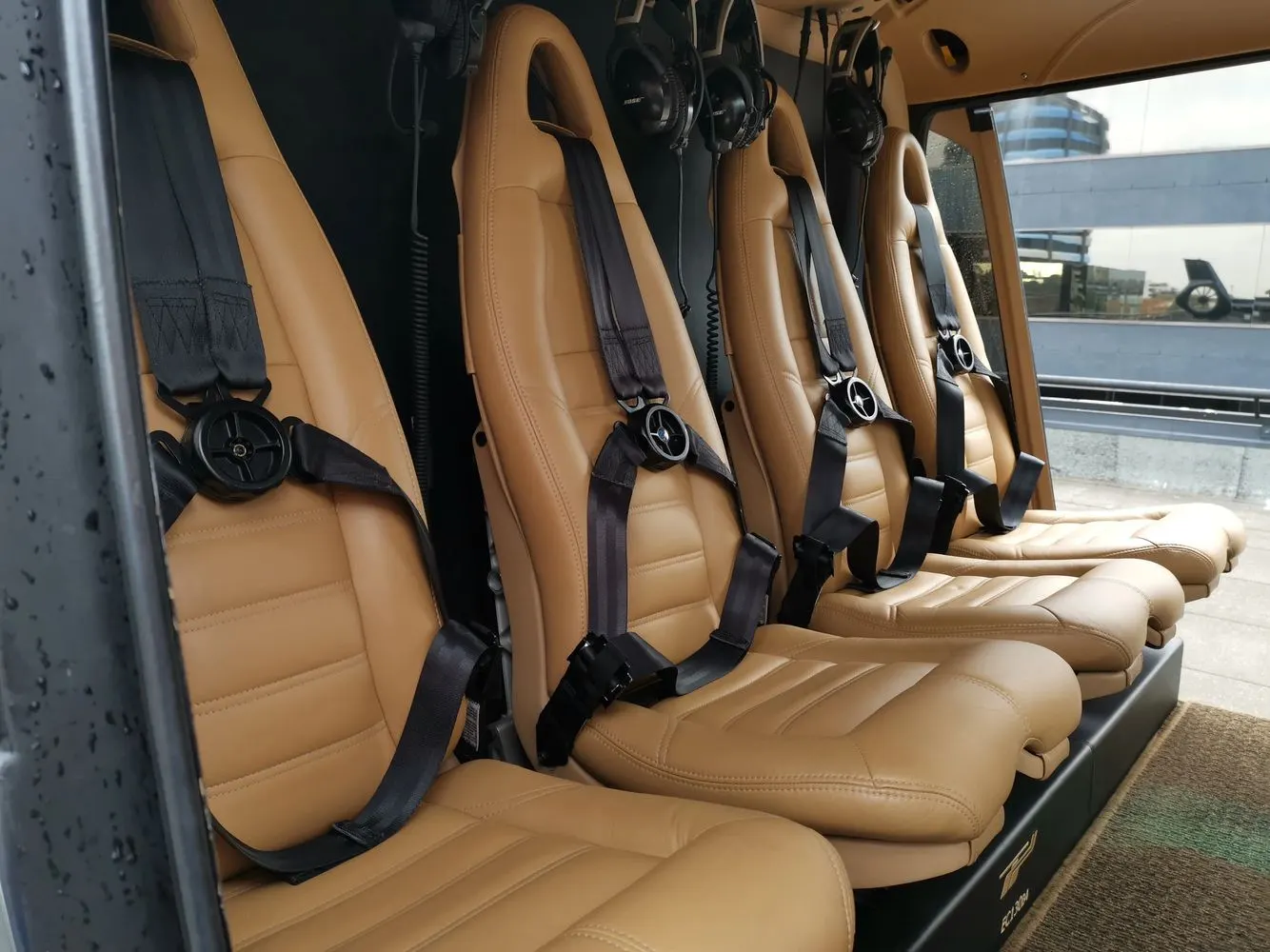 Row of tan leather helicopter seats with cleaned harnesses