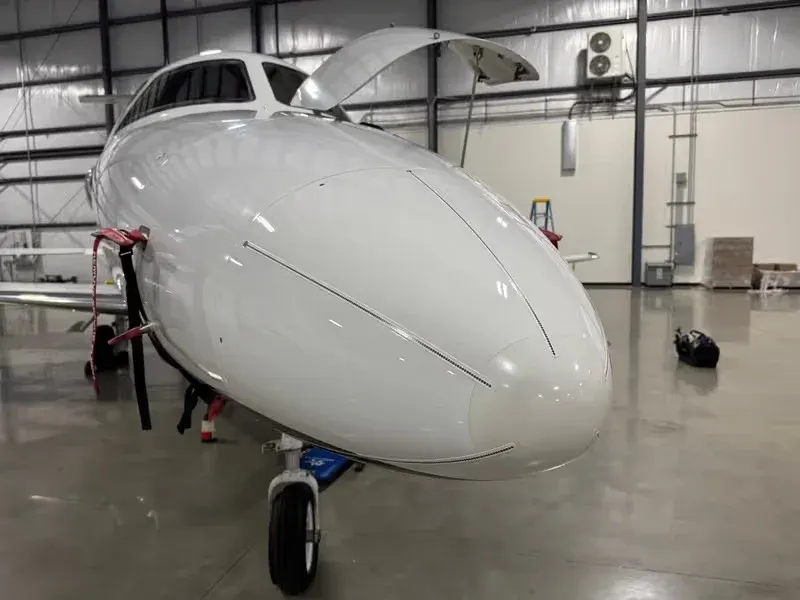 Midsize jet nose and open cabin door inside a hangar