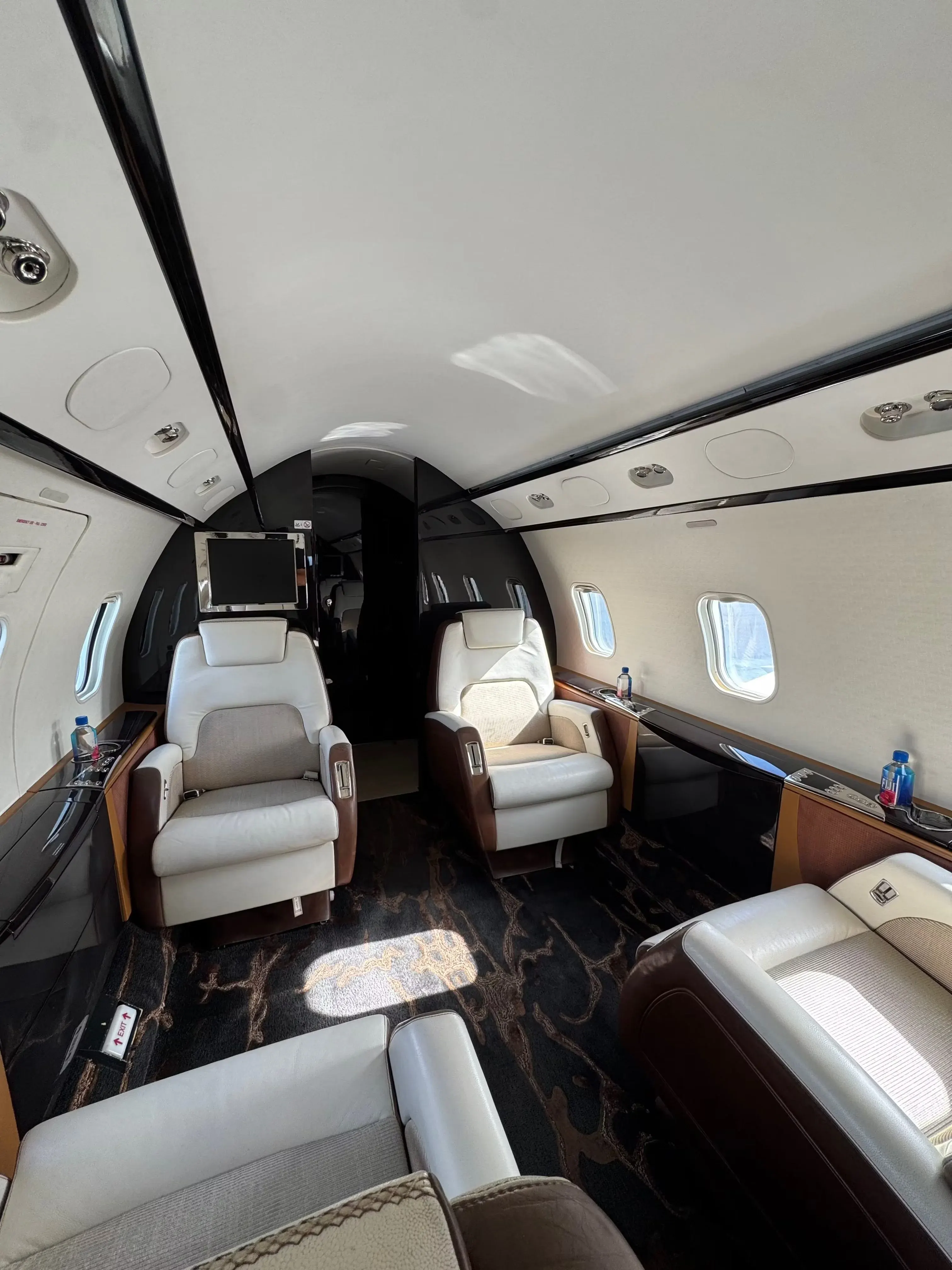 Large-cabin business jet interior with tan leather seating and stone table